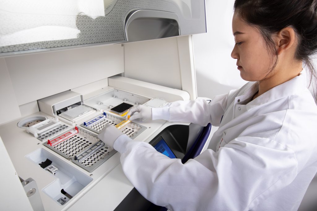 A lab technician loads reagents into Thermo Fisher Scientific’s Ion Torrent Genexus System