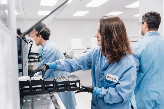 Image of researchers in a lab adding samples to a Helix sequencing machine.